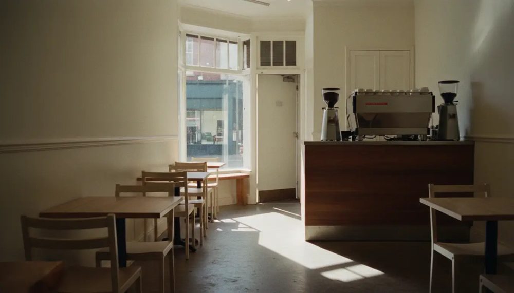 The room inside, small tables and a counter in warm daylight