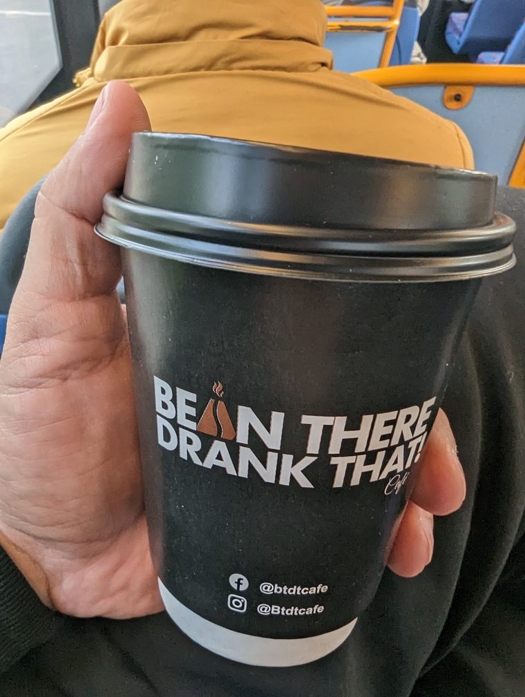 A takeaway coffee cup held up to the camera